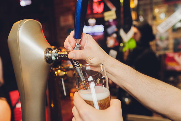 close-up of barman hand at beer tap pouring a draught lager beer. - Valokuva, kuva
