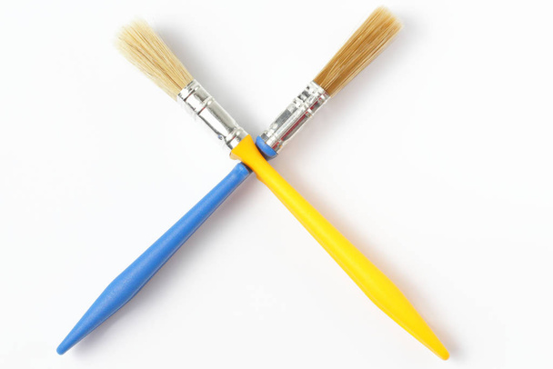 Crossed two paint brushes close-up on a white background. - Fotoğraf, Görsel