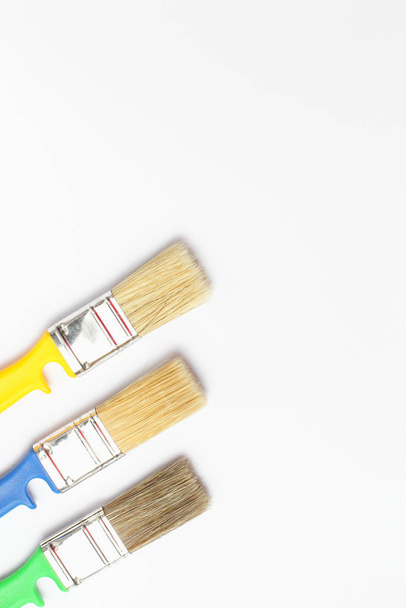 Close-up of color paint brushes on a white background, place for text, vertical frame, flat lay. - Fotoğraf, Görsel