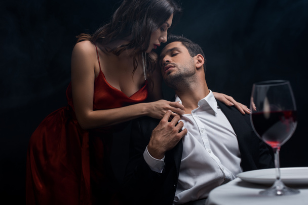 El foco selectivo de la mujer hermosa desabotonar camisa de novio durante la cena romántica aislado en negro
 - Foto, imagen