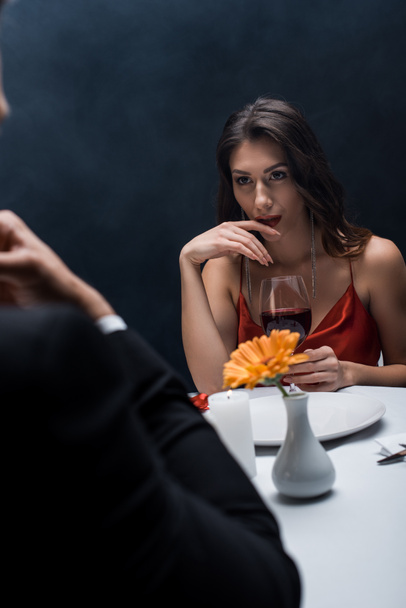 foyer sélectif de belle femme regardant petit ami à la table servie sur fond noir avec de la fumée
 - Photo, image