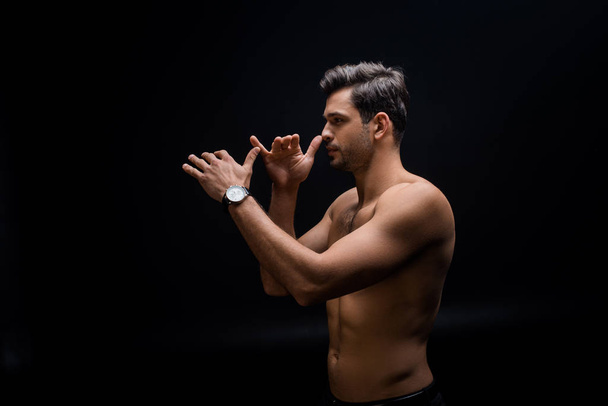 Side view of handsome shirtless man gesturing isolated on black - Foto, Bild