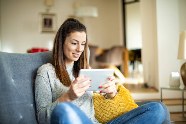 Attractive woman with digital tablet relaxing at home  - 写真・画像