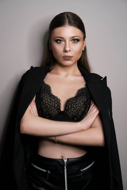 Beautiful young white girl close-up in a black jacket on a gray background - Fotografie, Obrázek