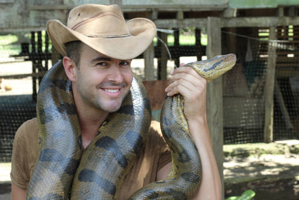 Homem mostrando carinho por uma cobra gigante
 - Foto, Imagem