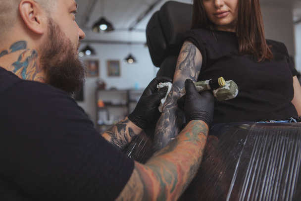 Young attractive woman getting new tattoo by professional tattoo - Foto, afbeelding