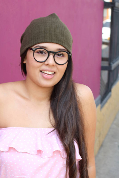 ritratto di una bella giovane donna in cappello rosa e occhiali da sole in piedi sulla strada - Foto, immagini