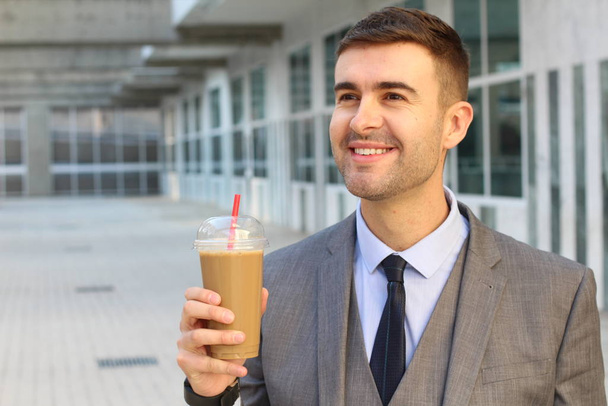 közeli kép jóképű fiatal üzletember műanyag csésze hideg kávé ital az utcán - Fotó, kép