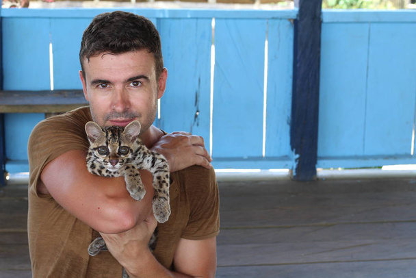 Handsome man holding a baby ocelot - Photo, Image
