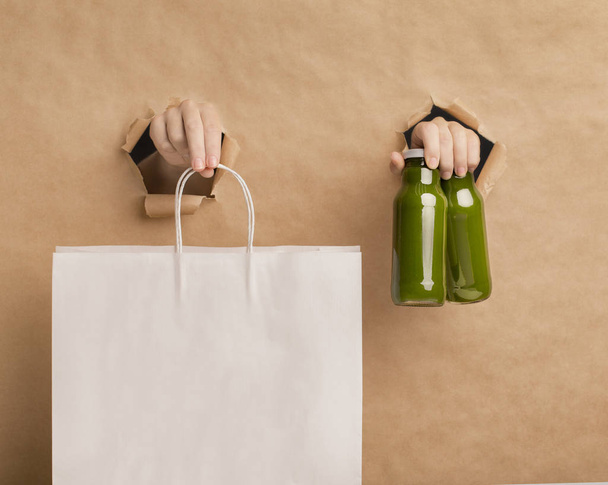 Batido de desintoxicación de jugo verde saludable y manos femeninas sosteniendo una bolsa de papel
 - Foto, imagen