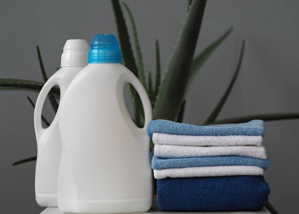 The concept of eco-friendly natural detergents. Detergents and cleaners with aloe vera plant on a gray background in a plastic laundry basket. Village. - Foto, Imagem
