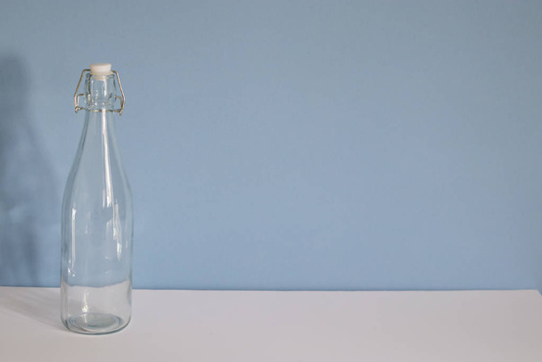 Empty glass bottle on a blue white background - Foto, afbeelding