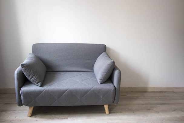 Szürke kanapé párnákkal a hatvanas évek stílusában a belső térben. - Fotó, kép