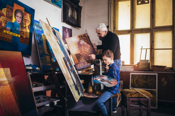 Father and son working and painting together in art studio - Valokuva, kuva