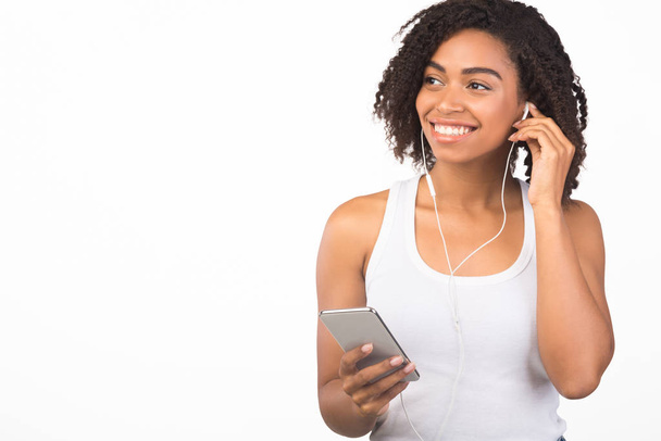 Усміхнений афро жінка слухає музику, дивлячись вбік
 - Фото, зображення