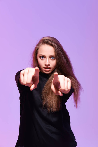 studio shot of young woman pointing at camera  - Foto, Imagen
