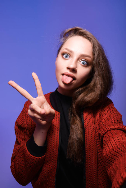 studio shot of young woman showing victory gesture - Foto, afbeelding