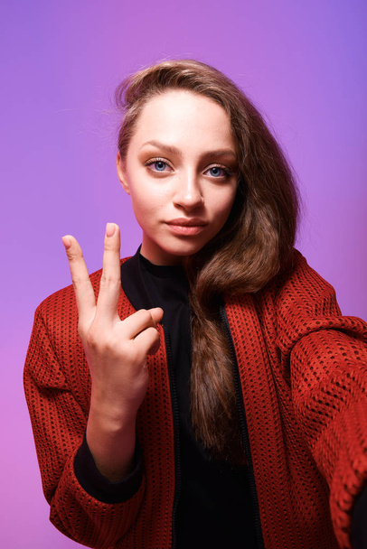 studio shot of young woman showing victory gesture - Foto, imagen