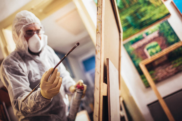 Restorer working on the painting at restoration workshop - Photo, Image