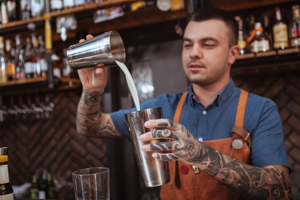 Handsome male tattooed bartender preparing a drink - Photo, Image
