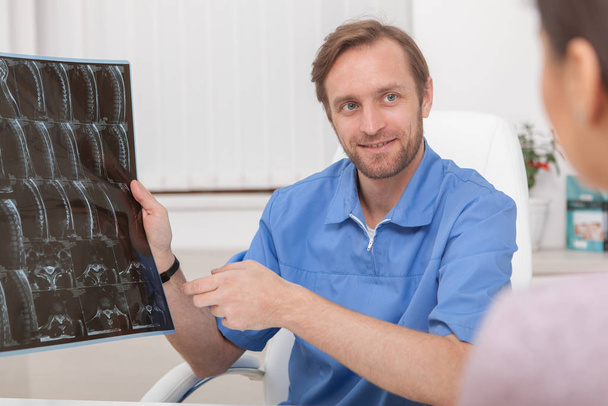 Mature male doctor examining MRI scan of a patient - Фото, изображение