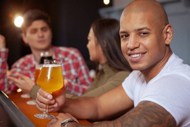 Diverse group of friends drinking beer at the pub together - Photo, Image