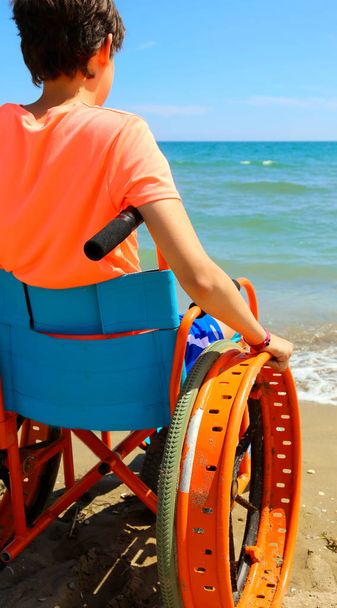 молодий perosn на інвалідному візку дивиться на море
 - Фото, зображення
