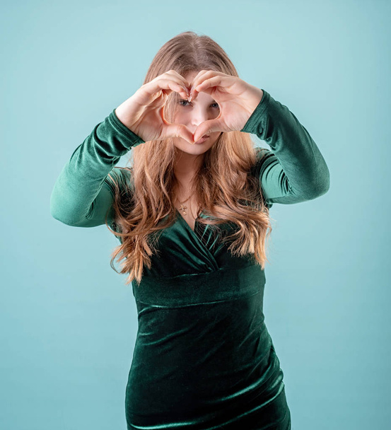 Young sexy woman showing heart sign on blue background - Φωτογραφία, εικόνα