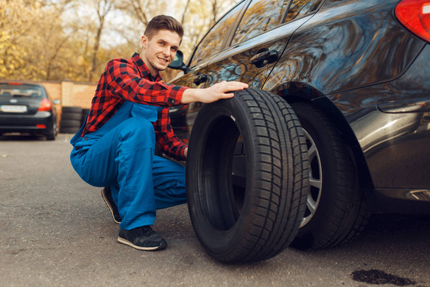 タイヤ、タイヤサービスの均一な固定問題の男性労働者。車の修理サービスやビジネス、壊れた車輪を修復する男 - 写真・画像