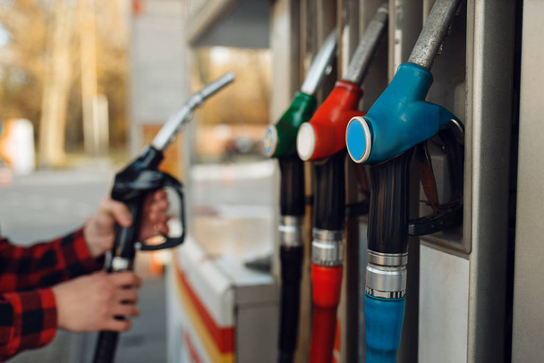 Un trabajador de uniforme toma un arma en una gasolinera, repostando combustible. Servicio de carga de gasolina, gasolina o diesel
 - Foto, Imagen