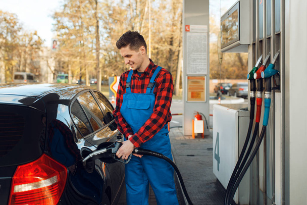 Male worker in uniform fuels car on gas station, fuel filling. Petrol fueling, gasoline or diesel refuel service - Photo, Image