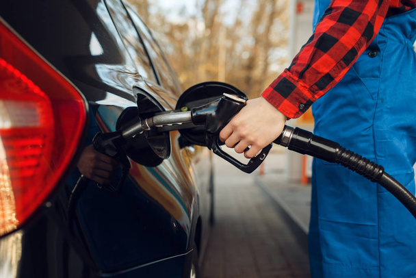 Male worker in uniform fuels vehicle on gas station, fuel filling. Petrol fueling, gasoline or diesel refuel service - Foto, afbeelding