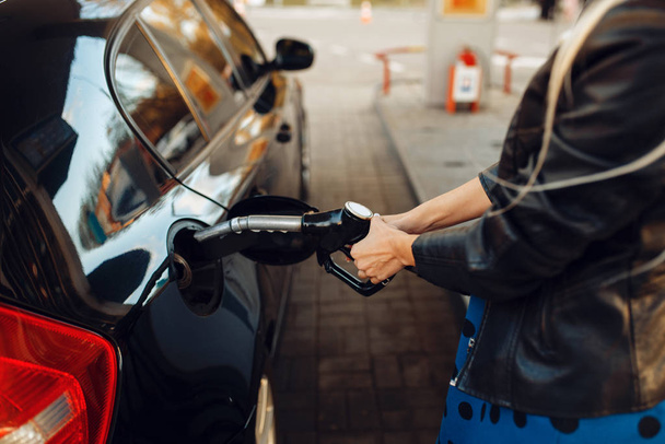 Woman with gun fuels vehicle on gas station, fuel filling. Petrol fueling, gasoline or diesel refuel service, - Foto, Imagem