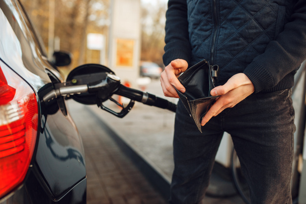 ガソリンスタンドに空の財布を持つ男、燃料充填。ガソリン又はディーゼル燃料の燃料供給 - 写真・画像