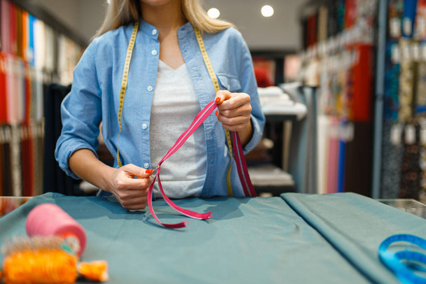 Seamstress con cinta de medición y trituradora, taller textil. Mujer trabaja con tela para costura, mujer a la medida en el lugar de trabajo, vestuario. - Foto, Imagen