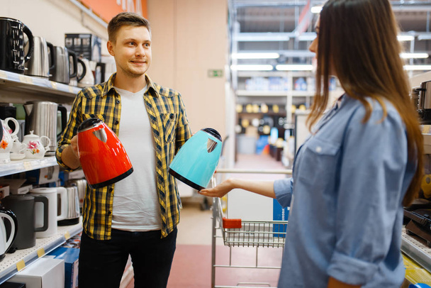 Young couple choosing electric kettle in electronics store. Man and woman buying home electrical appliances in market - Фото, зображення