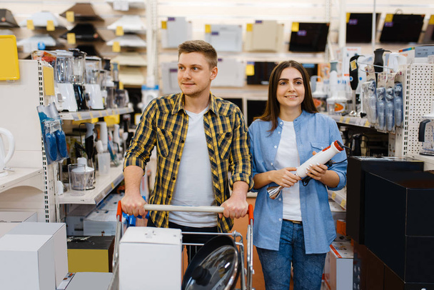 Młoda para trzyma mikser elektryczny w sklepie elektronicznym. Mężczyzna i kobieta kupujący domowe urządzenia elektryczne na rynku - Zdjęcie, obraz