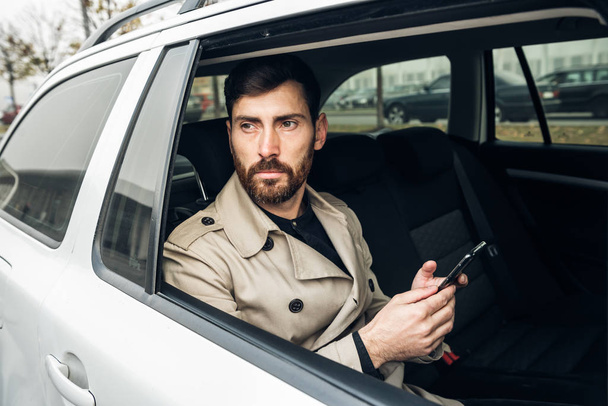 Empresario usando smartphone mientras viaja en taxi
. - Foto, imagen