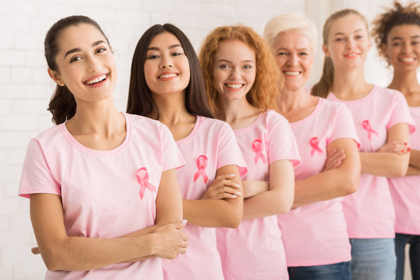 Mesdames avec des rubans roses sur T-shirts posant sur fond blanc
 - Photo, image