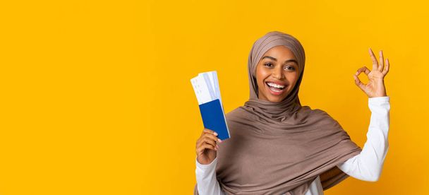 Happy black muslim girl with passports and tickets gesturing ok sign - Photo, Image