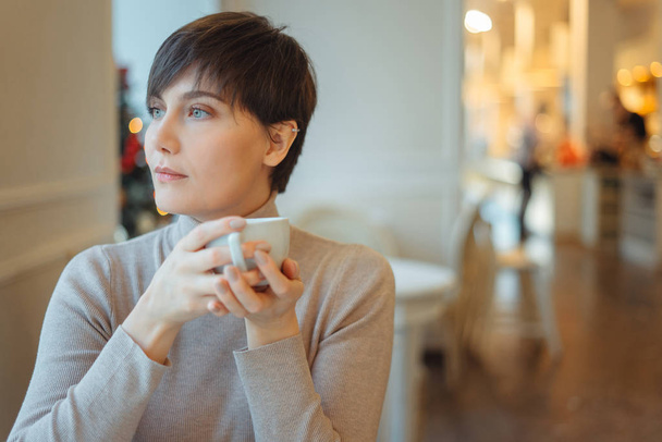 Frau hält Tasse und trinkt Kaffee am Morgen im Café während des Frühstücks - Foto, Bild