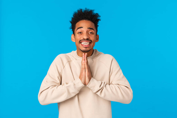 Pretty please I need your help. Charismatic cute and silly african-american young guy begging lend car, press palms together in pray, supplication gesture, smiling as pleading over blue background - 写真・画像