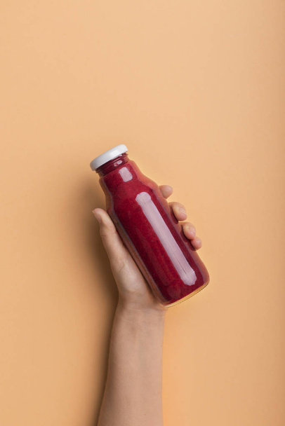 Nainen käsi tilalla pullo sokerijuurikkaan detox smoothie
 - Valokuva, kuva