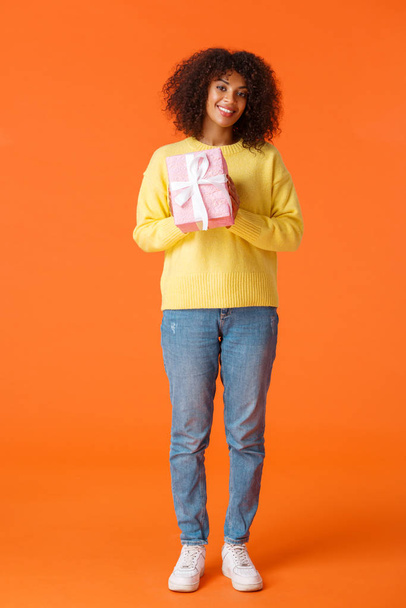 Full-length pionowe ujęcie słodkie i przyjazne afrykańsko-amerykańska dziewczyna przygotowany prezent dla dziewczyny, stojąc z zapakowany prezent uśmiechnięty czuły aparat, chcesz pogratulować z Walentynki - Zdjęcie, obraz