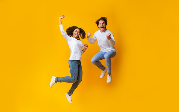 Cheerful girl and handsome guy jumping in air, having fun together - Photo, Image