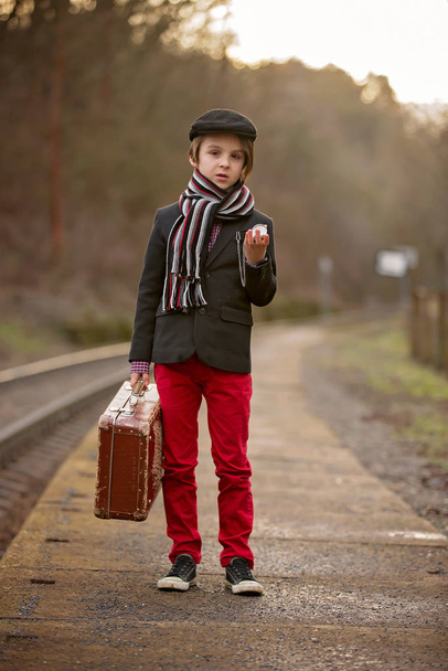 Adorable boy on a railway station, waiting for the train with su - Foto, Bild