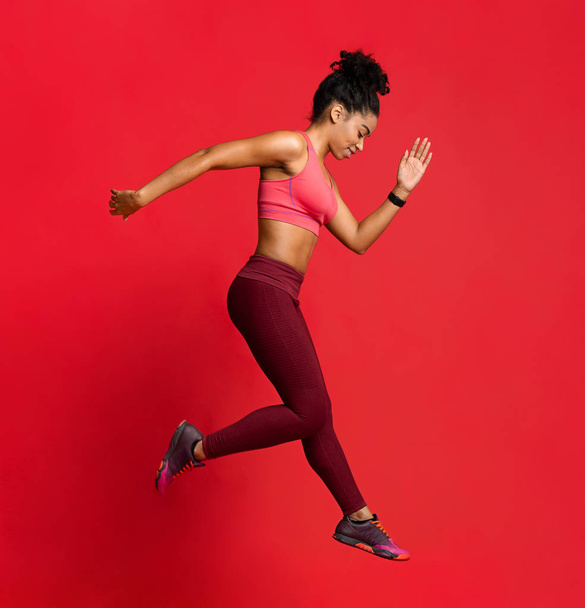 Αθλητική νεαρή γυναίκα που ασκεί πάνω από το κόκκινο φόντο - Φωτογραφία, εικόνα