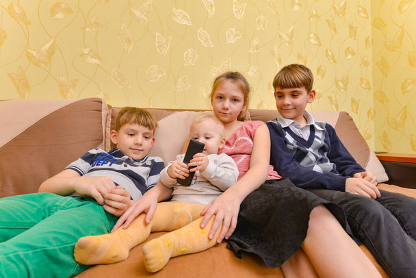 Щасливі і радісні діти сидять на дивані у вітальні
 - Фото, зображення