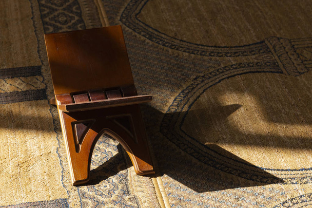 Soporte decorativo de madera para el Corán, en el suelo con una alfombra en la mezquita
. - Foto, Imagen
