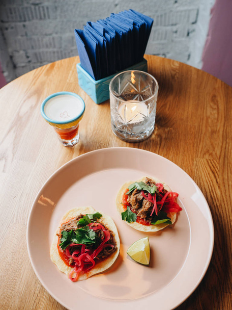 Tacos with meat, onion, greens, lime. plate on the table - Фото, изображение
